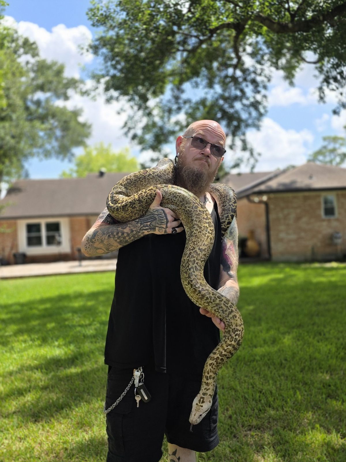 Tank standing outdoors with a giant python around his shoulders