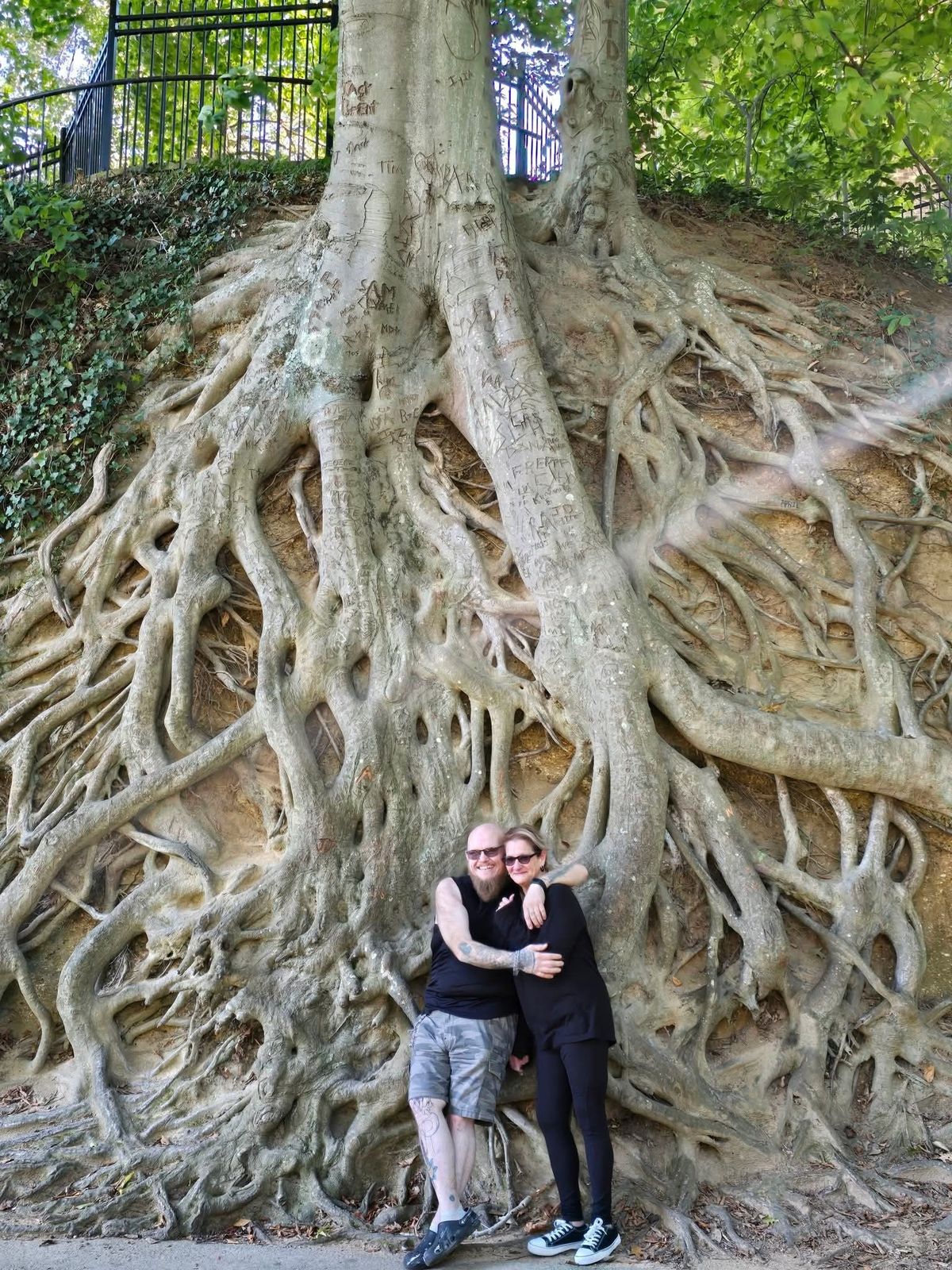 Tank and Sandra standing together beneath giant tree roots
