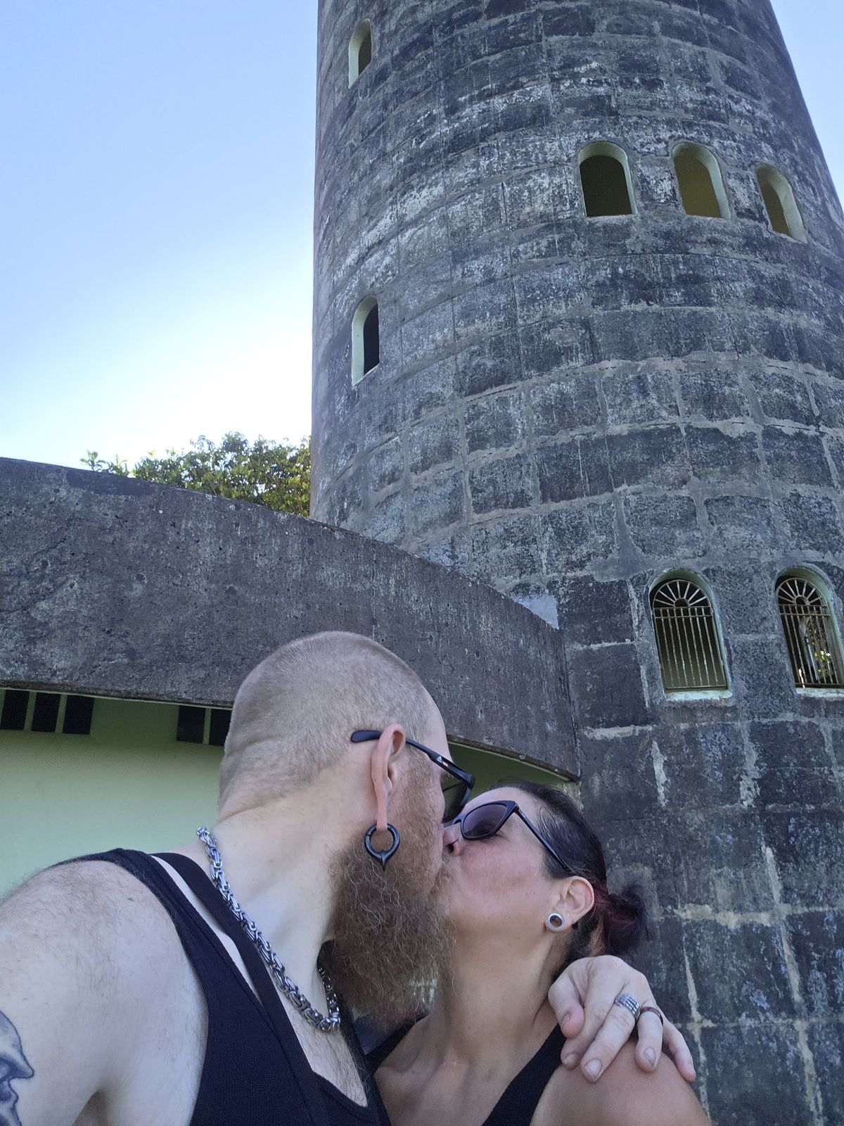 Tank and Sandra kissing beside a stone tower